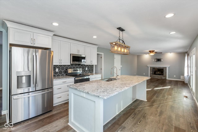 kitchen with white cabinets, a center island with sink, sink, ceiling fan, and stainless steel appliances