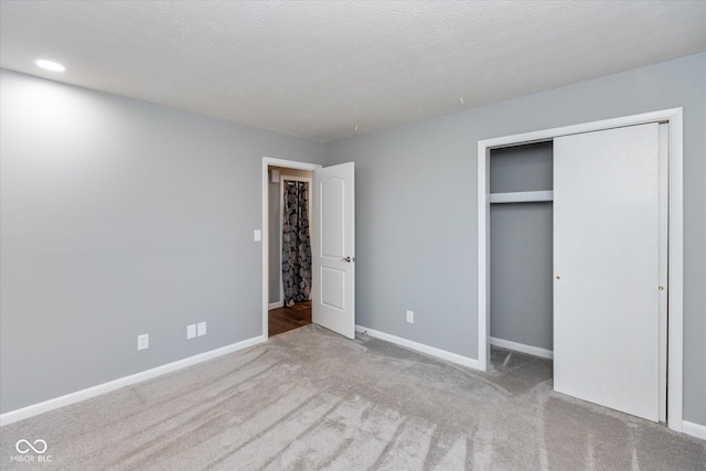 unfurnished bedroom featuring light carpet, a textured ceiling, and a closet