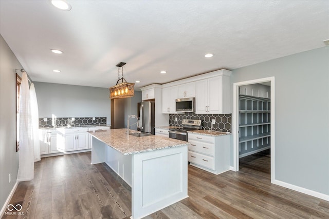 kitchen with stainless steel appliances, light stone counters, pendant lighting, decorative backsplash, and white cabinets