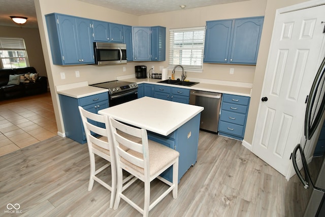 kitchen featuring light wood-type flooring, stainless steel appliances, blue cabinets, and sink