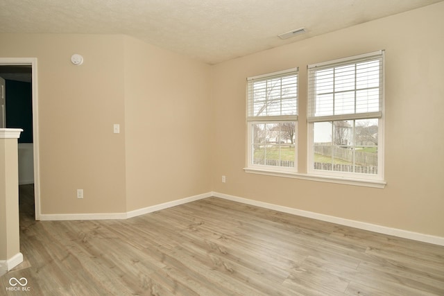 spare room featuring a textured ceiling and light hardwood / wood-style floors