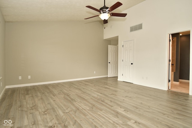 empty room featuring ceiling fan, high vaulted ceiling, and light wood-type flooring