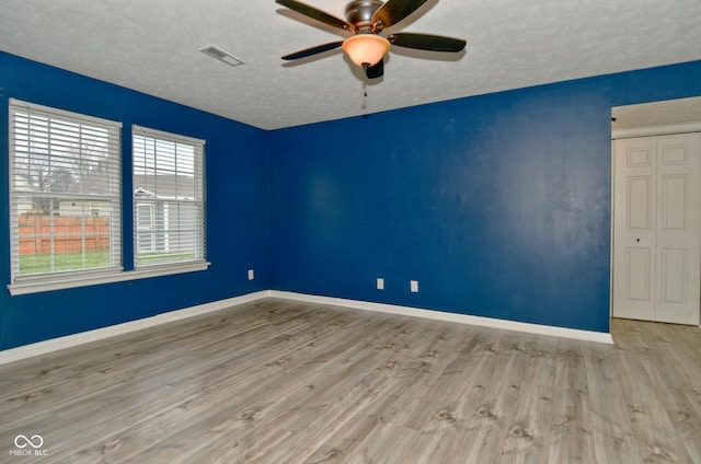 unfurnished room with a textured ceiling, light hardwood / wood-style floors, and ceiling fan