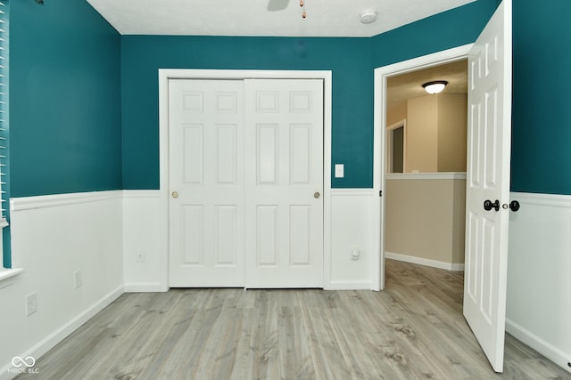 unfurnished bedroom with ceiling fan, a closet, a textured ceiling, and light wood-type flooring