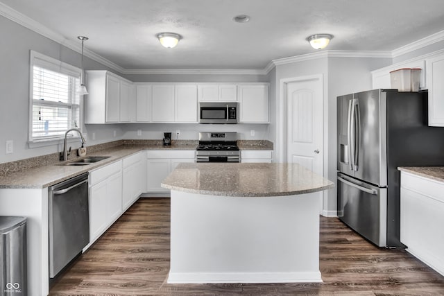 kitchen featuring appliances with stainless steel finishes, sink, pendant lighting, white cabinets, and a center island