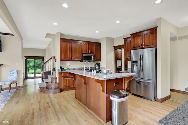 3592 W Smokey Row Rd, Bargersville, IN 46106 - kitchen featuring stainless steel appliances, light wood finished floors, light stone counters, an island with sink, and a breakfast bar