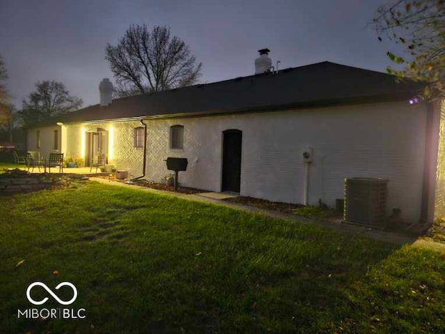 back house at dusk with a yard and cooling unit