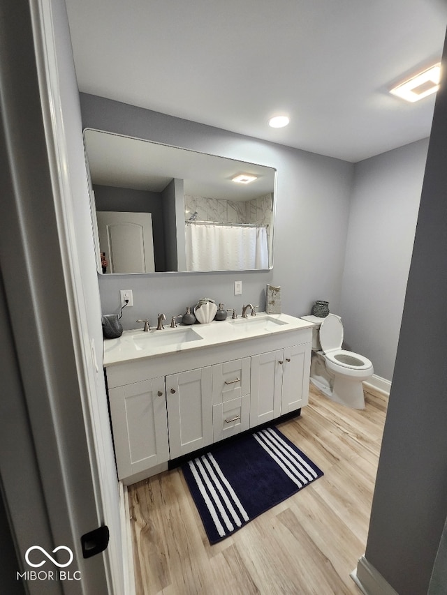 bathroom with hardwood / wood-style floors, vanity, toilet, and walk in shower