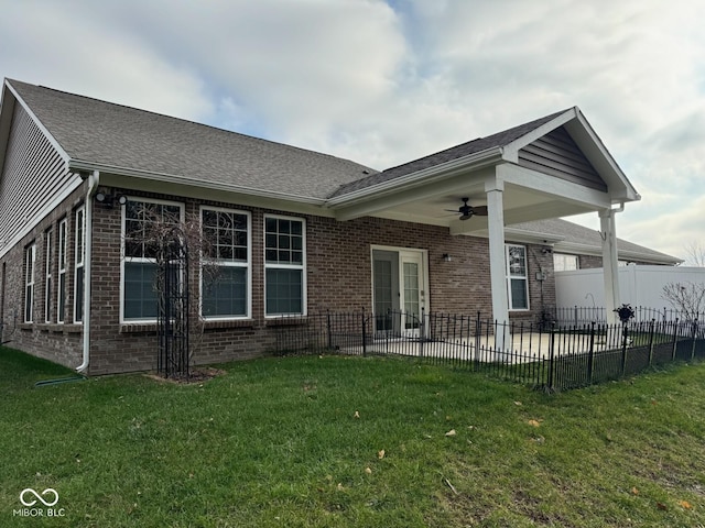 back of property with ceiling fan, a patio, brick siding, fence, and a yard