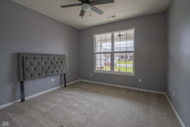 carpeted empty room featuring ceiling fan, visible vents, and baseboards