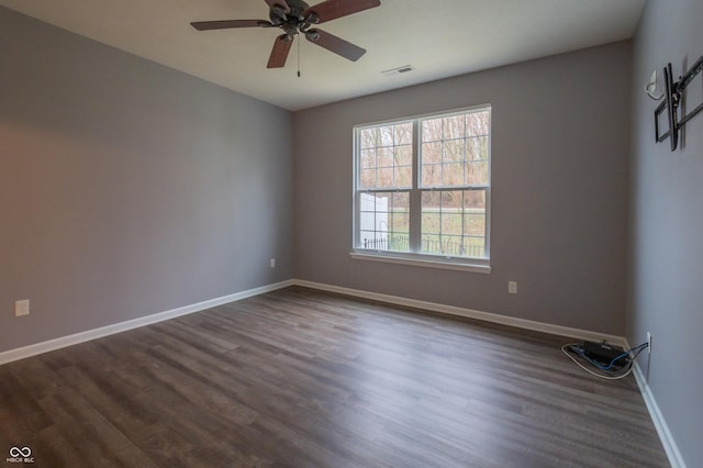 unfurnished room with dark wood-type flooring, a ceiling fan, visible vents, and baseboards