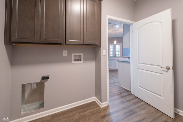 clothes washing area with cabinet space, hookup for a washing machine, baseboards, and wood finished floors