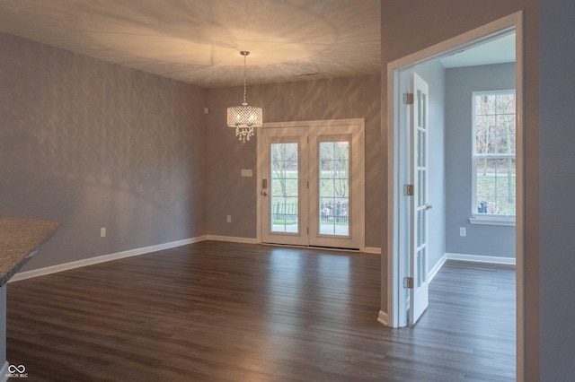 unfurnished dining area with an inviting chandelier, dark wood finished floors, and baseboards