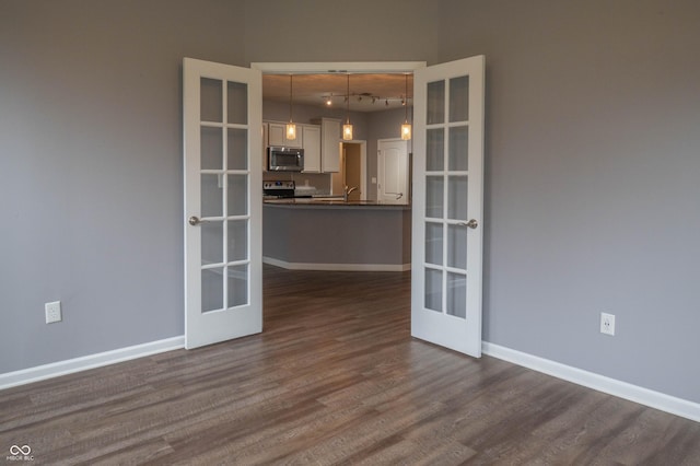 spare room with dark wood-style floors, baseboards, and french doors