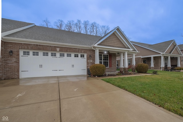 craftsman inspired home with brick siding, a shingled roof, an attached garage, a front yard, and driveway