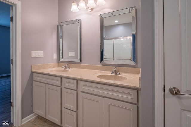 bathroom featuring a shower with shower door, a sink, and double vanity