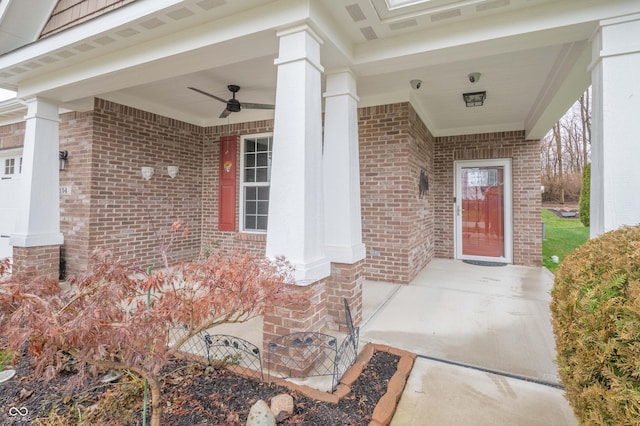 view of exterior entry featuring covered porch, brick siding, and a ceiling fan