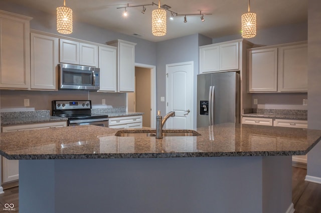 kitchen with stainless steel appliances, a sink, white cabinets, dark wood-style floors, and a center island with sink