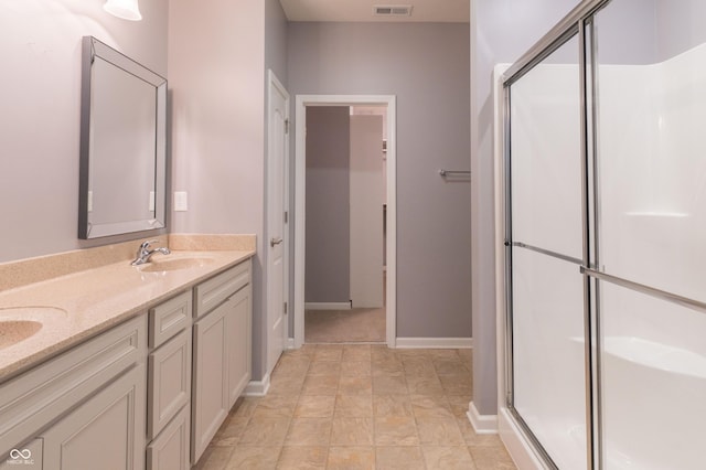 bathroom featuring double vanity, a stall shower, visible vents, baseboards, and a sink