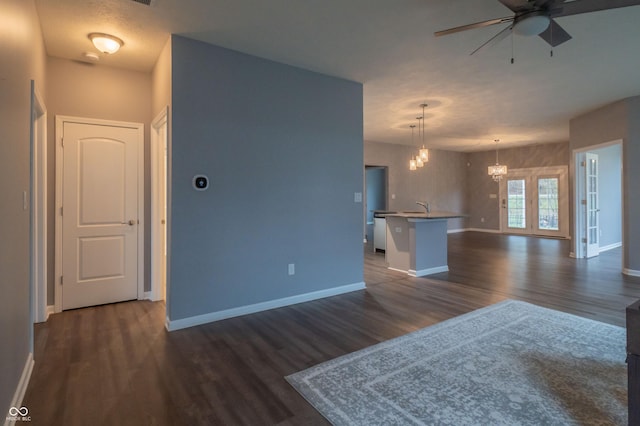 interior space featuring open floor plan, dark wood-type flooring, and baseboards