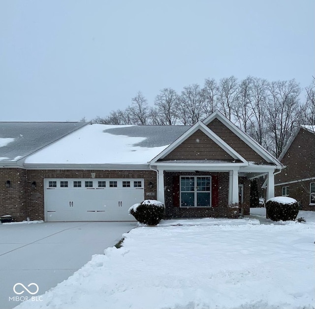 craftsman-style house featuring an attached garage, driveway, and brick siding