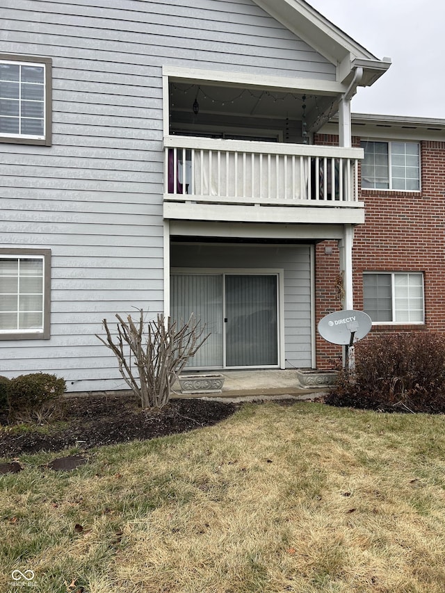 rear view of property featuring a balcony and a lawn