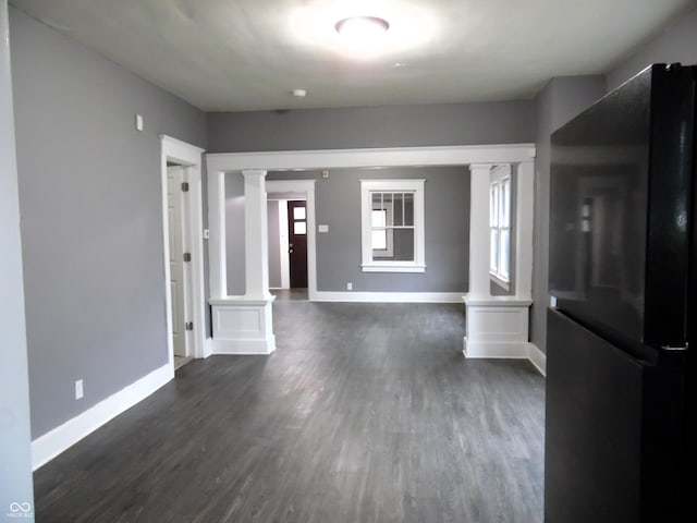 unfurnished living room with decorative columns and dark hardwood / wood-style floors