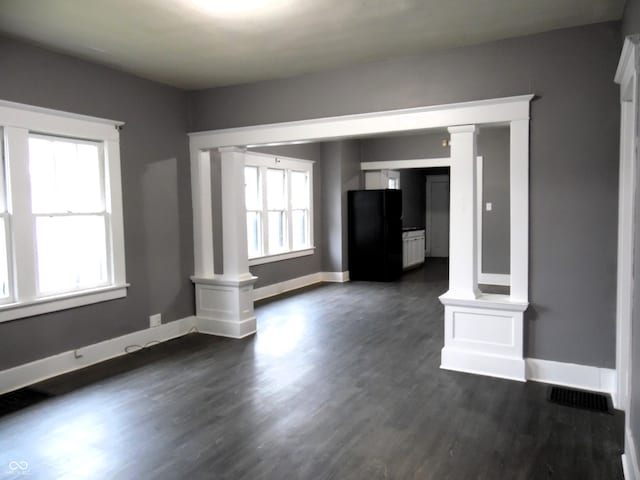 unfurnished living room featuring decorative columns and plenty of natural light