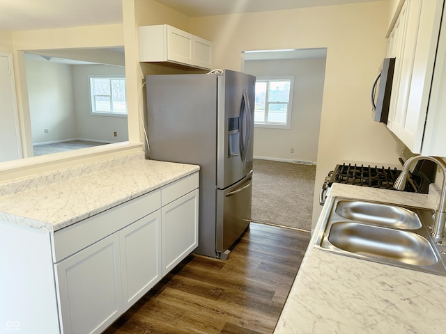 kitchen with appliances with stainless steel finishes, dark hardwood / wood-style floors, white cabinetry, and sink