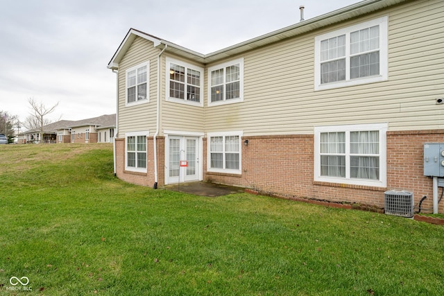 rear view of house with cooling unit and a lawn