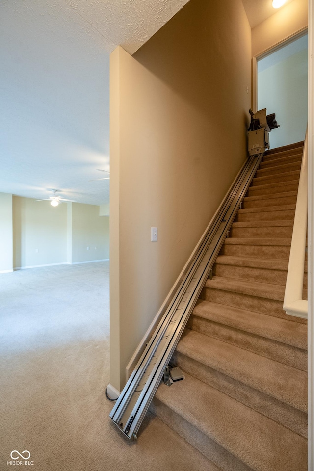 stairs with carpet floors and ceiling fan