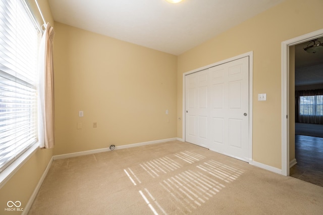 unfurnished bedroom featuring light colored carpet, a closet, and multiple windows