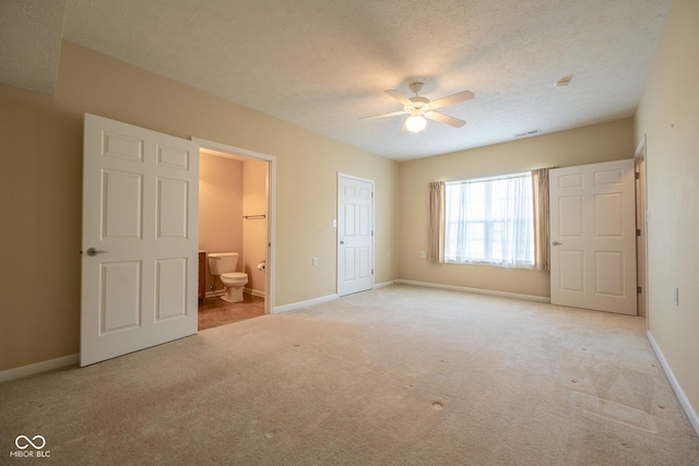 unfurnished bedroom with ceiling fan, ensuite bath, light carpet, and a textured ceiling