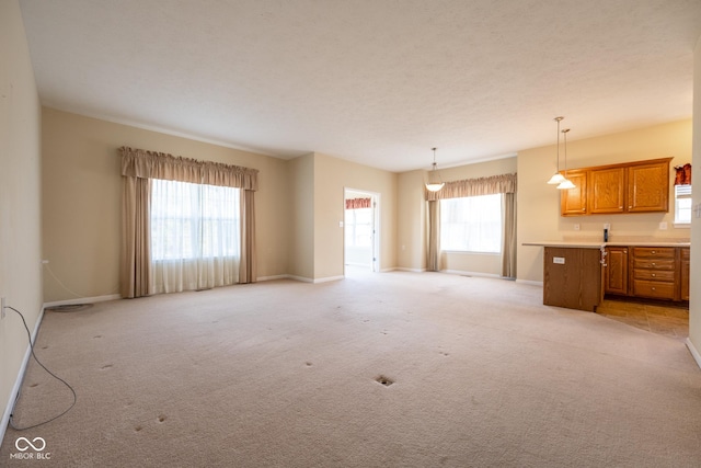 unfurnished living room featuring light colored carpet and a healthy amount of sunlight