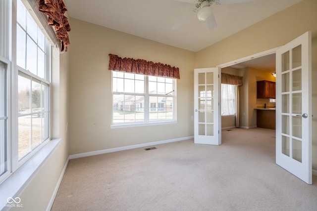 carpeted spare room featuring plenty of natural light, ceiling fan, and french doors