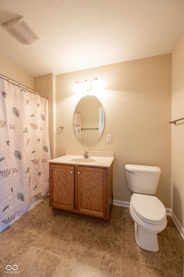 bathroom with vanity, toilet, and a textured ceiling