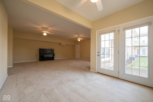 unfurnished living room featuring ceiling fan, light colored carpet, and plenty of natural light