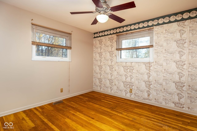 spare room with a wealth of natural light, ceiling fan, and wood-type flooring