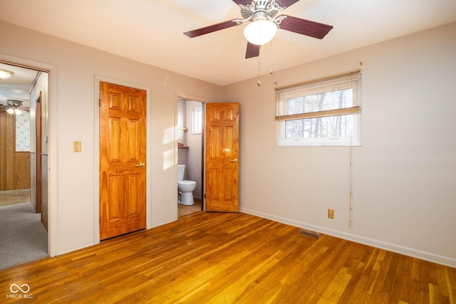 unfurnished bedroom featuring hardwood / wood-style floors, ensuite bathroom, and ceiling fan