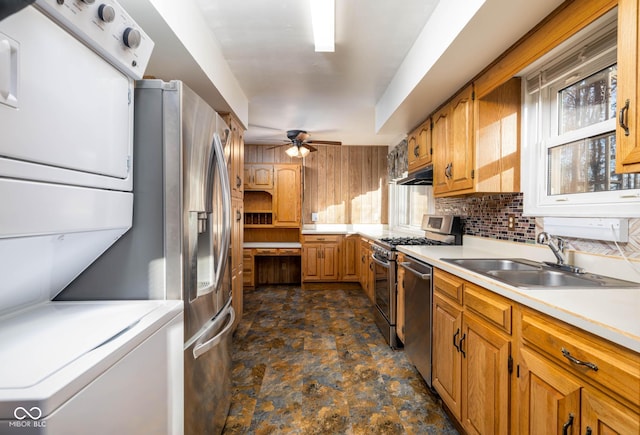 kitchen with tasteful backsplash, stainless steel appliances, ceiling fan, sink, and stacked washer and clothes dryer