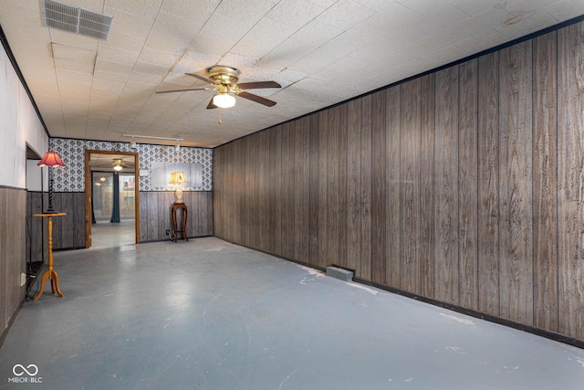 basement featuring wooden walls and ceiling fan