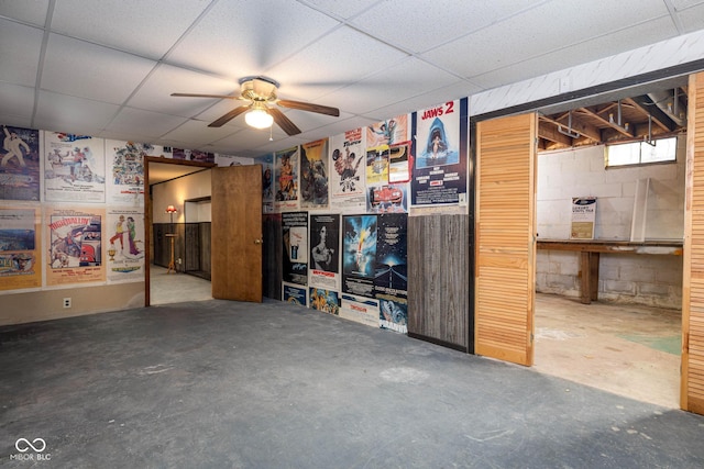 basement featuring a paneled ceiling and ceiling fan