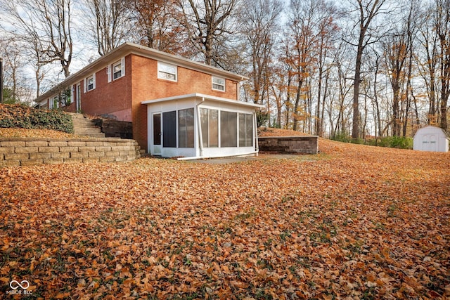 back of house with a sunroom and a storage unit