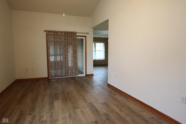 spare room with dark hardwood / wood-style floors and vaulted ceiling