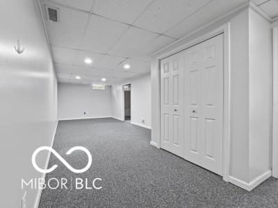 basement featuring a paneled ceiling and dark colored carpet