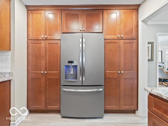 kitchen featuring light stone countertops, stainless steel fridge with ice dispenser, tasteful backsplash, and light hardwood / wood-style flooring