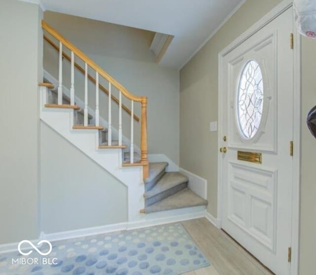 foyer featuring light wood-type flooring and ornamental molding