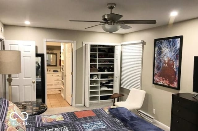 tiled bedroom featuring ceiling fan, a baseboard radiator, and ensuite bath