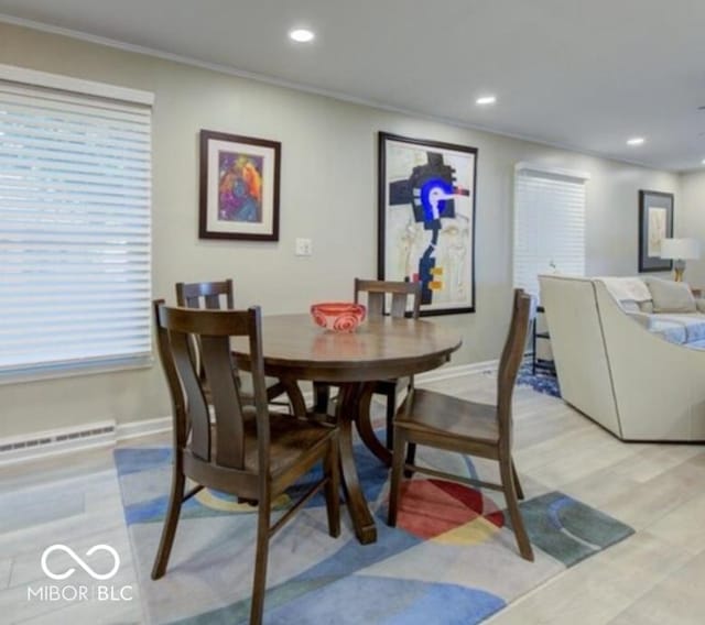 dining area featuring a healthy amount of sunlight, light wood-type flooring, crown molding, and a baseboard heating unit