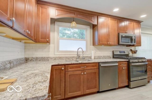 kitchen with backsplash, light stone countertops, sink, and appliances with stainless steel finishes